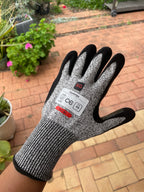 Angled back view of a SiteGrips cut-resistant glove with its safety label visible.