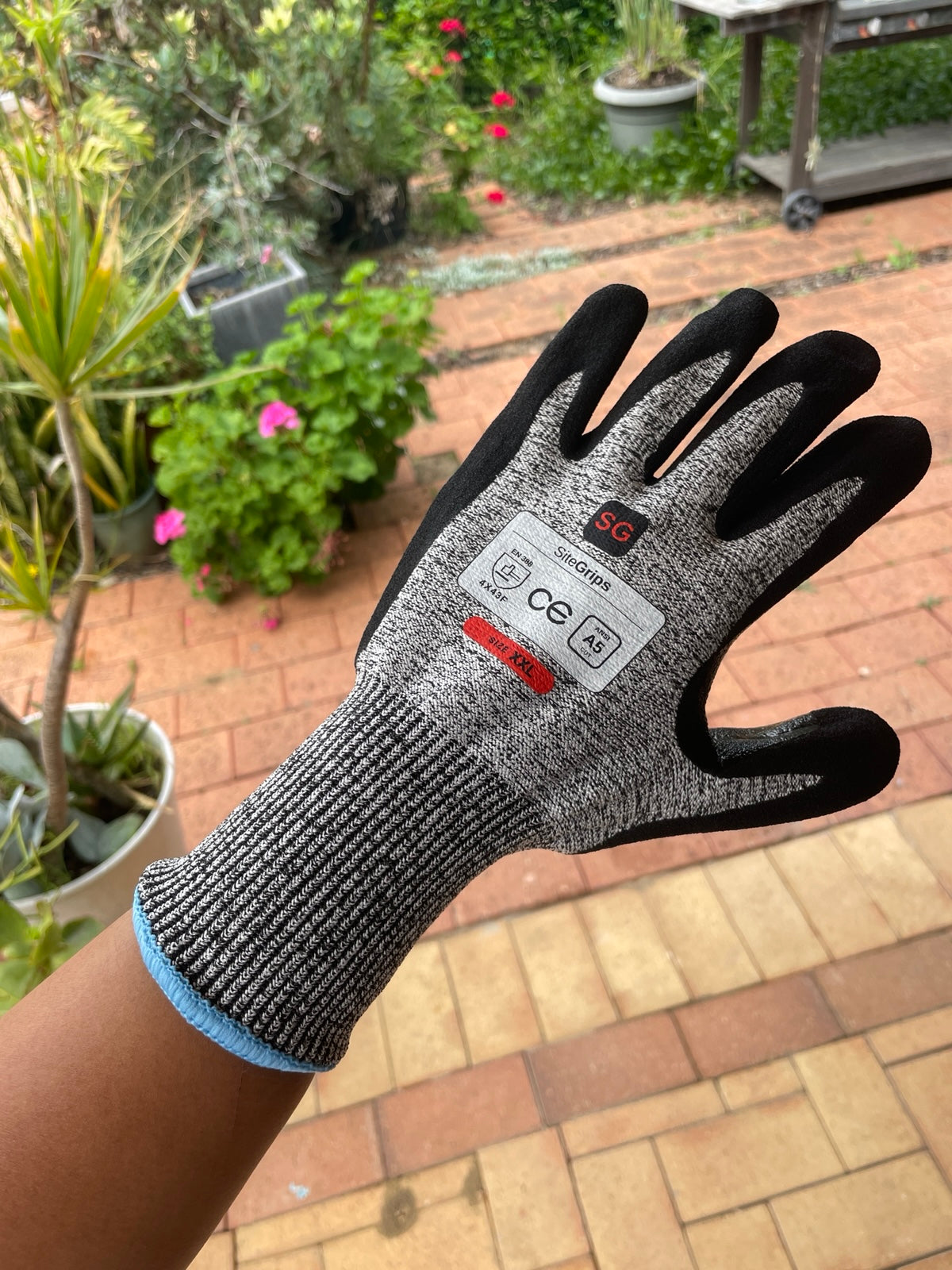 Angled close-up of a SiteGrips glove showing the woven shell, safety label and cuff.
