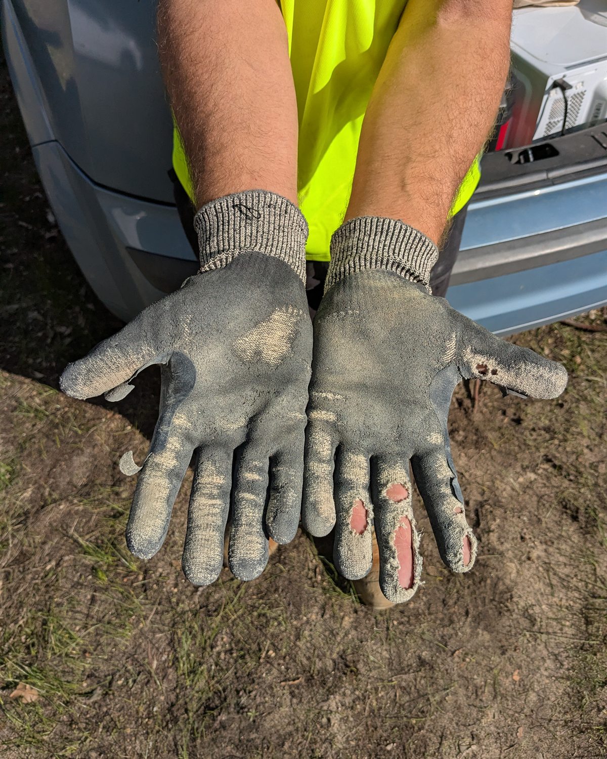 Heavily worn Sitegrips gloves with holes through several coated fingers